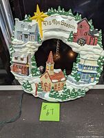 Full front view of the ceramic Christmas wreath showing the village buildings, the star, and Tis The Season banner.