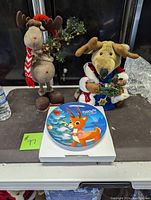 Photo showing the mouse and reindeer plush standups along with the Rudolph Christmas plate in front of them.