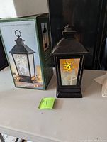 Photo of the Christmas decorative lantern standing next to its original box showing the overall appearance and condition of the lantern and box.