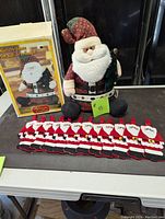 Full lot including 15 inch Santa doll with box and 12 Santa cutlery holders displayed in front
