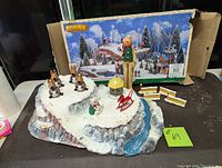 Porcelain snow-covered village base with four reindeer, gazebo, rocking horse, dog, gingerbread man, and two additional landscape pieces. Original Lemax box behind.