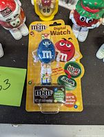 Blue digital M&M's watch sealed in original packaging with candy and digital display showing 5:00.
