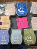 Photo showing 9 partially used Scentsy wax melts in various colors and scents arranged on a surface.