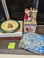 View of the Christmas Carol clock, star-shaped decorative plate, and Santa with Christmas tree tea light holder arranged together.