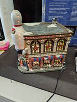 Side view showing the bowling pin with fiber optic lights glowing and wreath decorations on windows.