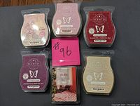 Top-down photo of six new Scentsy scented wax bars arranged on a black surface, showing colorful packaging and butterfly logo.