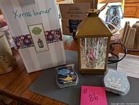 Photo of gold metal Scentsy burner with glass mirrored panels and decorative string lights, next to box labeled 'Xmas burner' and two scented wax bars on table.