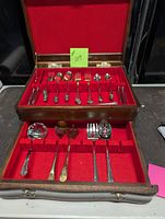 Overall view of the full silver cutlery set in wooden case showing 8 place settings and servers