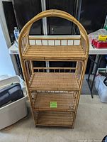 Front view of the 4-shelf wicker shelving unit showing all shelves and the arched top design.