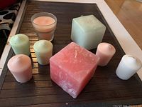 Eight aromatherapy candles displayed outside of box on black tray, showing colors and sizes.