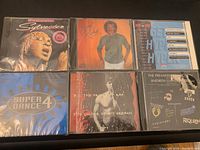 Front covers of six sealed vintage music CD cases arranged in two rows of three on a black surface.