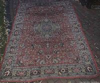 Full view of the traditional patterned carpet laid outdoors showing intricate central floral medallion design and border details