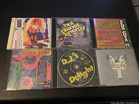 Top view of six vintage music CD cases with original cover art in varied genres including dance and techno.