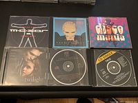 Top view of six CD jewel cases and sleeves, showing front covers with titles including M. S. Project, OMD, Disco Mania, Twilight, Trio, and Music For All It's Worth.
