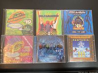 Front view of 6 vintage music compilation CDs in cases, showing colorful album art and titles.