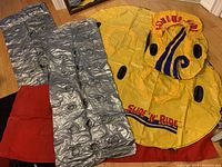 Shows three silver inflatable mattresses and three yellow inflatable water donuts with Slide-N-Ride branding, including a red accessory bag.
