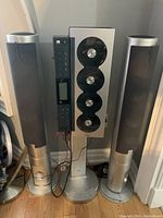 Full view of Sanyo 4-CD changer/tuner audio system flanked by two large tower speakers in silver with black details.