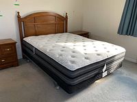Full view of mattress, box spring on metal bed frame with wooden headboard attached. Shows mattress and headboard condition and styling.