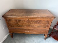 Frontal image of the vintage wooden blanket box displaying ornate carved wood details on the lid edges and front panel.