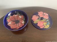 Top view of the pottery bowl open and the matching lid showing detailed floral patterns in pink, red, and green on deep blue background.