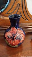 Front view of a Moorcroft vase showing deep blue glaze and red flower detail.