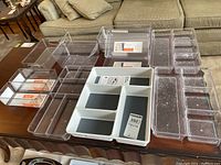 Photo showing full set of clear and white plastic drawer organizers of various sizes on a table.