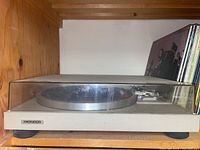 Full view of beige Pioneer record player turntable with plastic dust cover showing metal platter and tone arm.