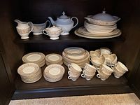 Shelved display of Royal Doulton china pieces including plates, cups, saucers and serving pieces
