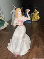 Front view of Royal Doulton porcelain figurine of a woman in white and pink dress holding a flower