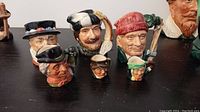 Photo showing the six Toby jugs including two miniatures, with detailed facial features and colored hats.