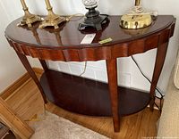 Side and front angle of demi lune table showing scalloped edges and legs