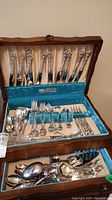Full view of upper and lower drawers filled with flatware in wooden case with turquoise lining