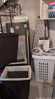 Laundry hampers and ironing board visible with water heater and piping in basement setting