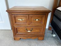 Front view of Thomasville vintage wooden nightstand showing drawer fronts with brass and ceramic pulls.