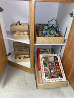 Cabinet shelf with two cardboard boxes of ornaments, one printed box of 12 ornaments and wire tinsel topper