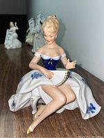 Front view of the Wallendorf porcelain figurine showing the seated lady holding a fan, wearing a blue bodice and white skirt with blue flowers.
