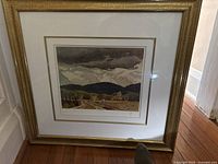 Framed AJ Casson print leaning against wall, showing gold frame and matting.