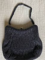 Front side view of the beaded evening purse showing geometric black and silver bead pattern and top clasp