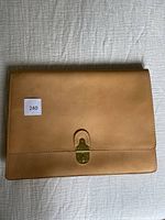 Front view of tan leather briefcase closed with brass closure