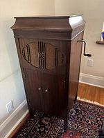 Front view of tall wooden console phonograph with patterned cloth grille and closed lid