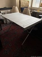 Full view of assembled aluminum collapsible dining table inside a room showing the entire tabletop and foldable legs.