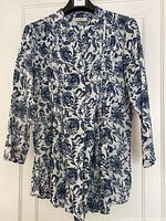 Mahogany blue paisley tunic shirt on hanger showing front and sleeve details.