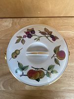 Top view showing the lid with painted fruits including blackberries and peaches and gold trim on lid handle and edge.