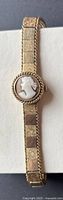 Full view of watch laid flat showing closed cameo cover and patterned bracelet