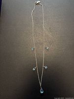 Full view of necklace laid flat showing chain and five aquamarine drops