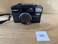 Front view of Minolta camera showing lens, built-in flash, and brand name