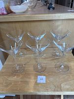 Six clear Spiegelau martini glasses arranged on wood surface