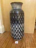 Front view of tall cobalt blue West German pottery vase showing embossed circular patterns and flared lip