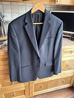 Blue wool Ralph Lauren men's jacket hanging on wooden hanger on kitchen counter.