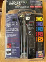 Front view of Monster PowerCenter PC700 surge protector in original packaging showing 8 color-coded outlets, packaging text, and features.